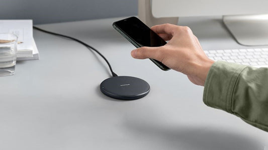 Hand holding phone over wireless charging pad